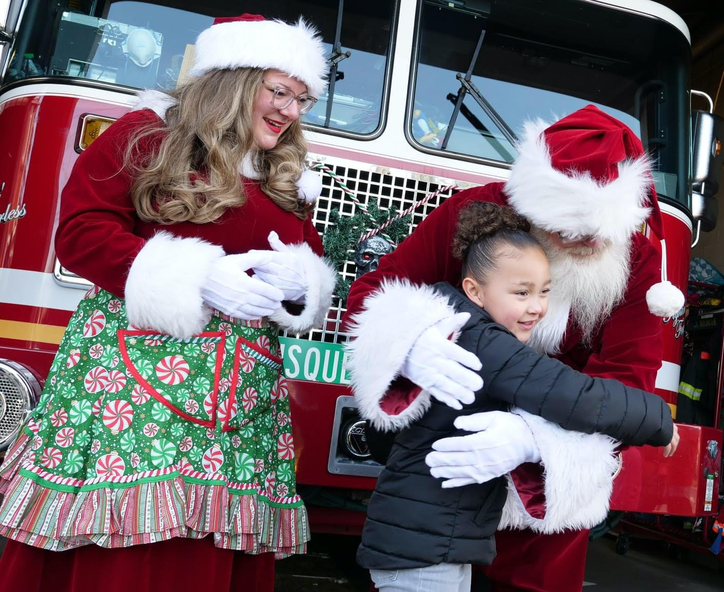 Santa and Mrs. Claus with child and firetruck